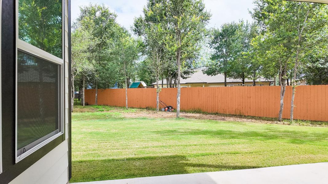 A spacious, verdant yard enclosed by a privacy fence, perfect for outdoor activities.