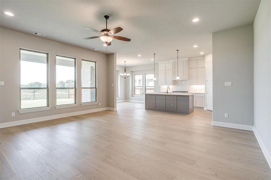 Unfurnished living room with ceiling fan with notable chandelier, light hardwood / wood-style floors, and sink