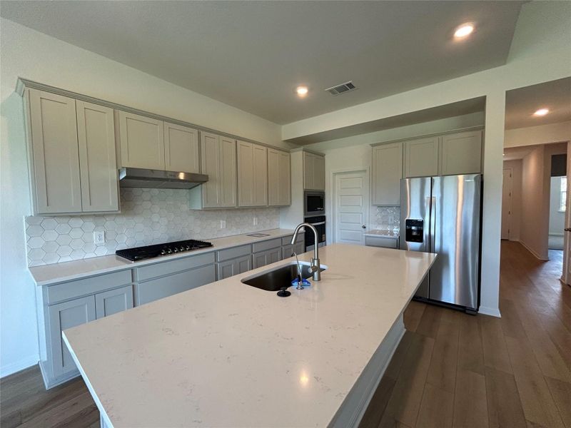 Kitchen with backsplash, appliances with stainless steel finishes, light stone counters, dark wood-style floors, and recessed lighting Kitchen with backsplash, appliances with stainless steel finishes, light stone counters, dark wood-style floors, and recessed lighting