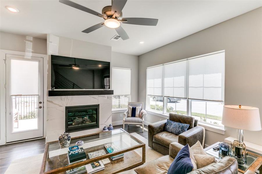 Living room featuring a premium fireplace, hardwood / wood-style floors, and ceiling fan