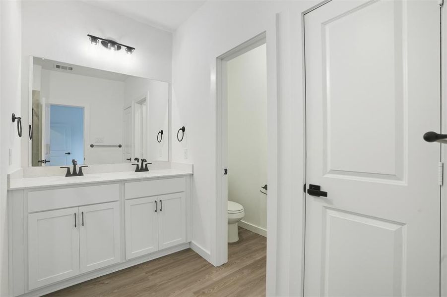 Full bathroom featuring double vanity and light wood-style flooring Full bathroom featuring double vanity and light wood-style flooring