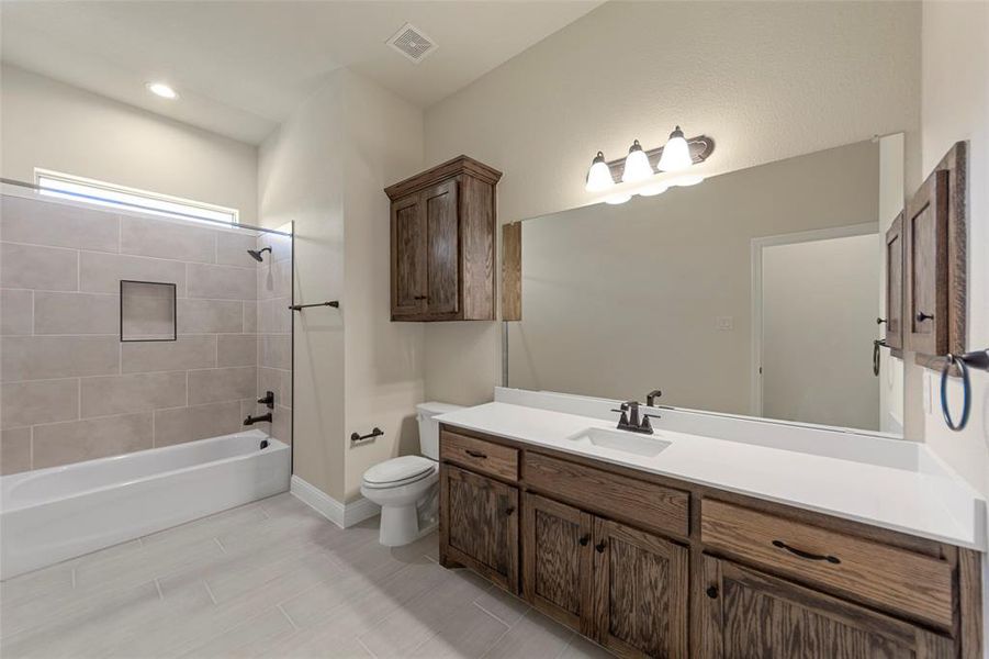 Full bathroom with toilet, vanity, and tiled shower / bath