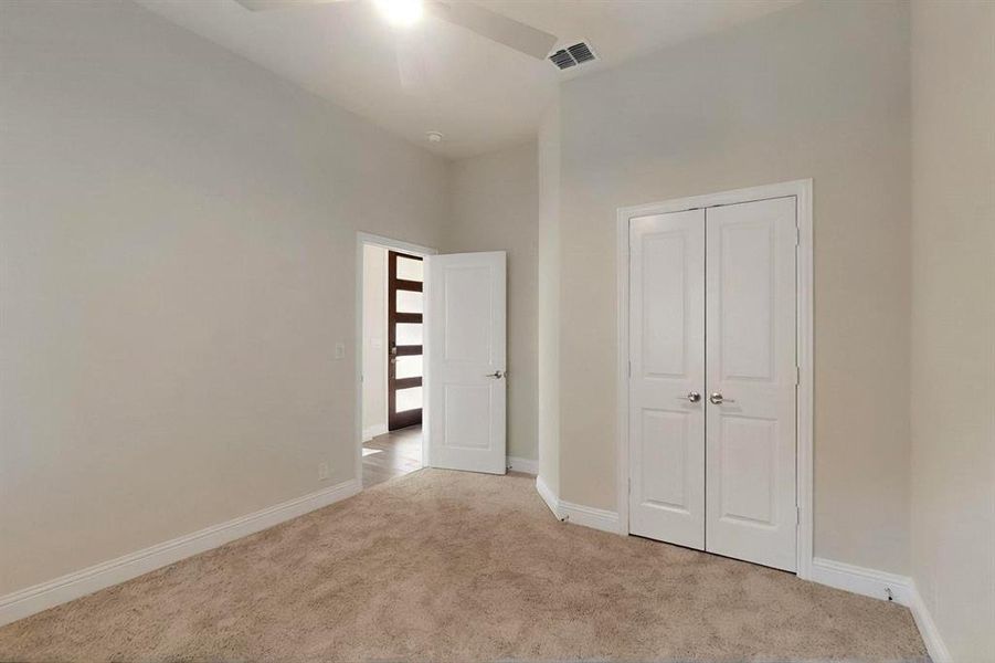 Unfurnished bedroom with carpet floors, baseboards, a closet, ceiling fan, and a towering ceiling