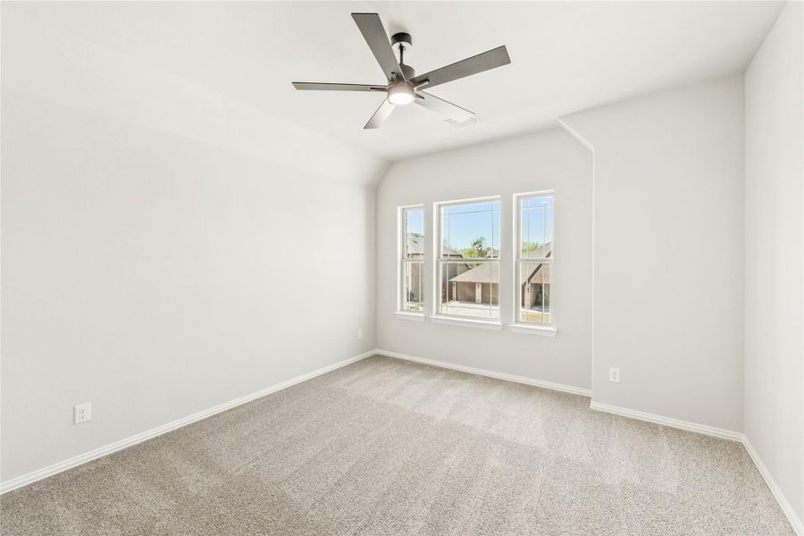 Empty bedroom with vaulted ceiling, ceiling fan, carpet flooring, and triple windows Empty bedroom with vaulted ceiling, ceiling fan, carpet flooring, and triple windows