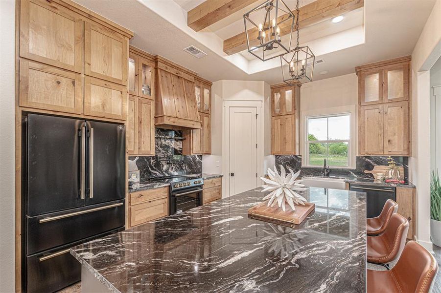 Kitchen featuring a raised ceiling, dark stone counters, freestanding refrigerator, a kitchen island, and tasteful backsplash