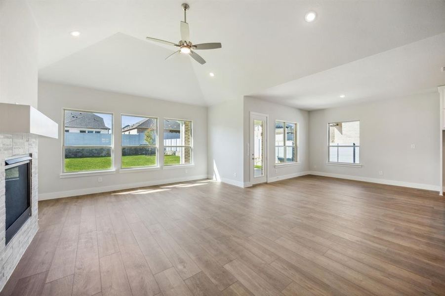 Unfurnished living room with plenty of natural light, ceiling fan, light wood-type flooring, and high vaulted ceiling