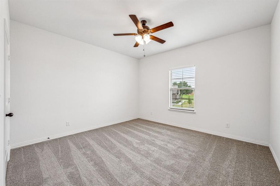 Carpeted empty room featuring ceiling fan