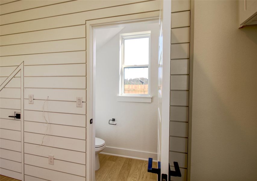 Powder room featuring light wood finished floors and toilet Powder room featuring light wood finished floors and toilet