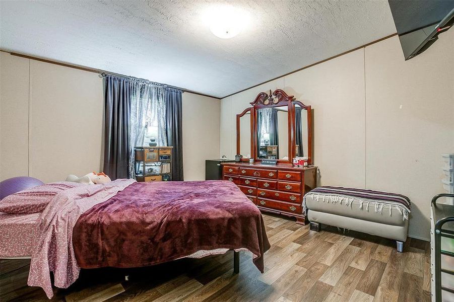 Bedroom featuring a textured ceiling, crown molding, and wood-type flooring