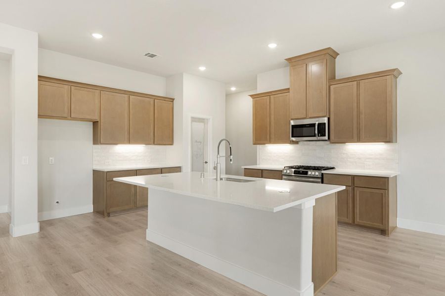 Open kitchen with large center island, light wood cabinets, white countertops, and stainless steel appliances Open kitchen with large center island, light wood cabinets, white countertops, and stainless steel appliances