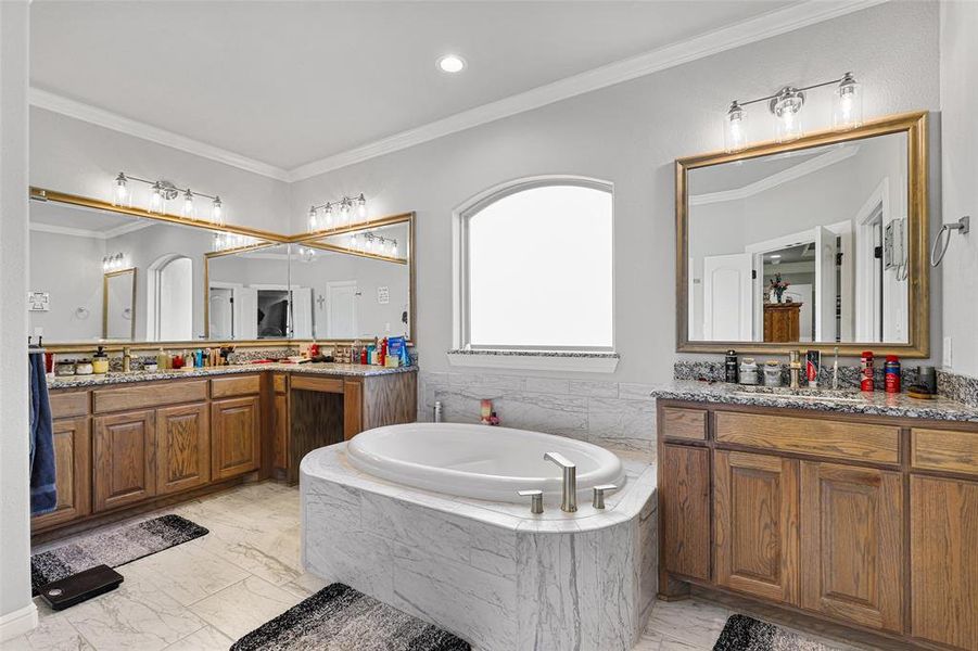 Bathroom with vanity, a relaxing tiled tub, and crown molding