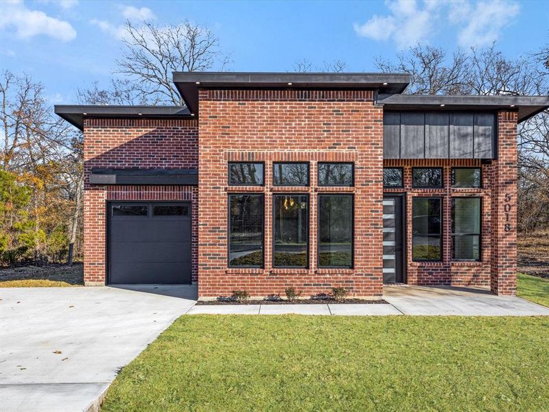 Rear view of property with driveway, brick siding, a lawn, and a garage Rear view of property with driveway, brick siding, a lawn, and a garage