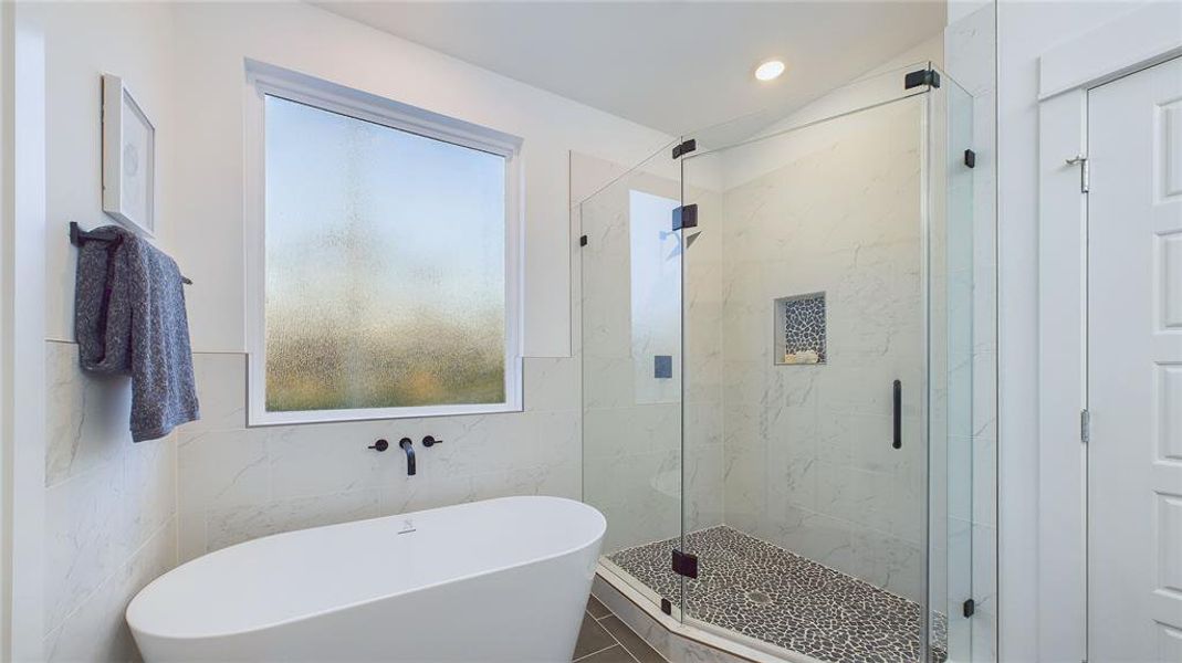 In the primary bath, enjoy the luxury of a separate shower and tub, complemented by abundant natural light for a serene and relaxing atmosphere