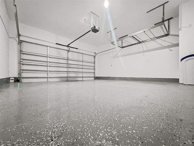 Garage with epoxy-finished flooring, storage, water softener, and EV charging outlet