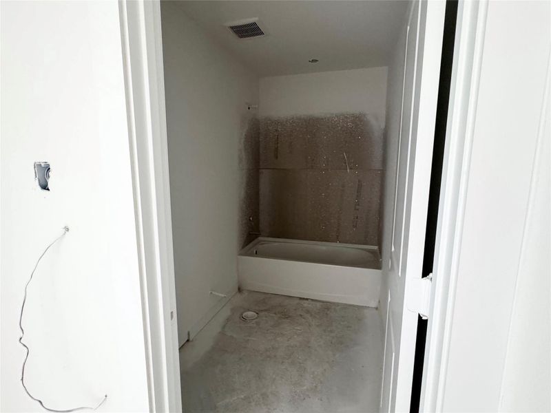 Bathroom featuring unfinished concrete flooring and shower / bathtub combination Bathroom featuring unfinished concrete flooring and shower / bathtub combination