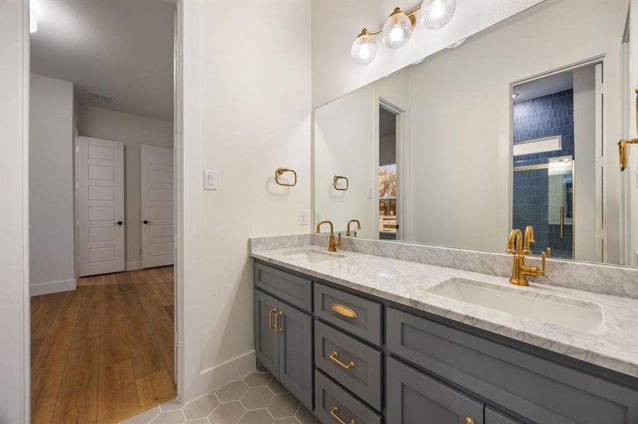 Full bath featuring double vanity and light wood-style flooring