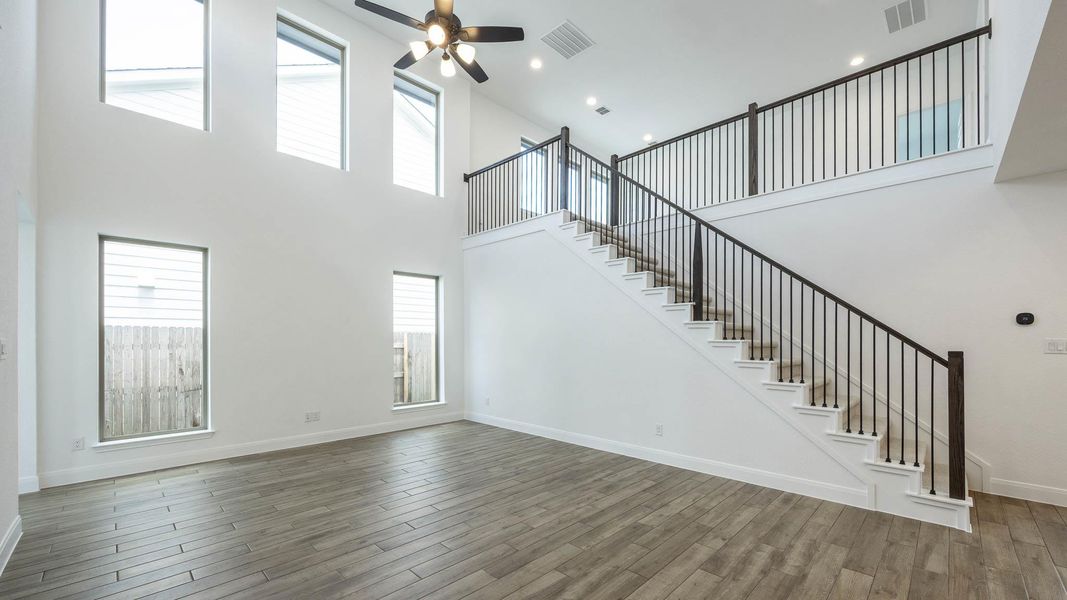Unfurnished living room with a high ceiling, wood finished floors, stairway, ceiling fan, and recessed lighting Unfurnished living room with a high ceiling, wood finished floors, stairway, ceiling fan, and recessed lighting