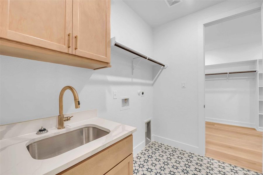 Clothes washing area with cabinet space, washer hookup, a sink, electric dryer hookup, and light floors Clothes washing area with cabinet space, washer hookup, a sink, electric dryer hookup, and light floors