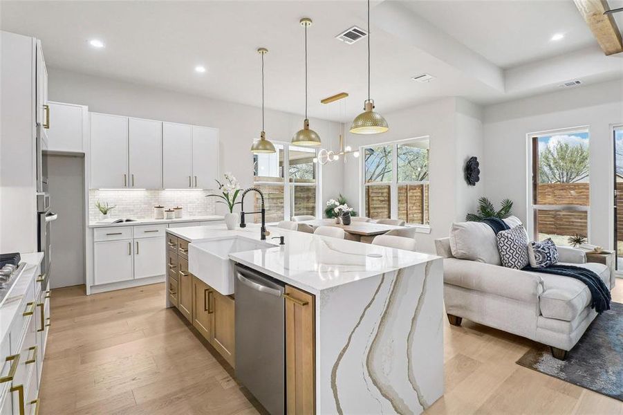 Modern kitchen featuring a waterfall island with a farmhouse sink, stainless steel appliances, white cabinetry, and wood-finish flooring