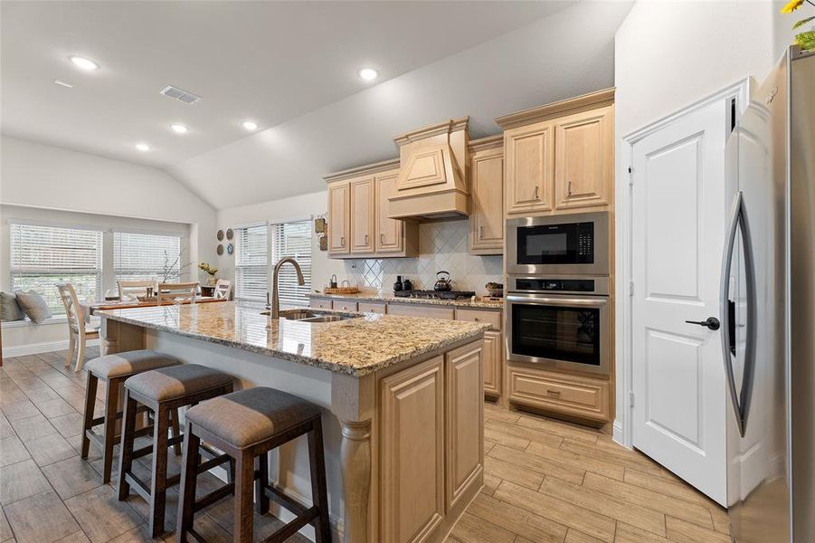 Kitchen featuring decorative backsplash, light stone countertops, recessed lighting, stainless steel appliances, and lofted ceiling Kitchen featuring decorative backsplash, light stone countertops, recessed lighting, stainless steel appliances, and lofted ceiling