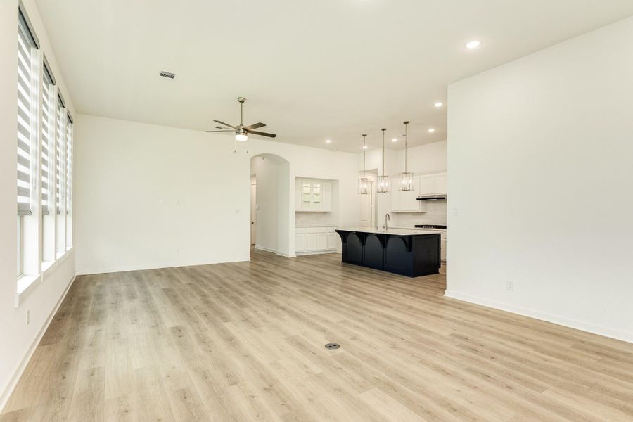 This view is taken from the rear of the family room, looking toward the kitchen. The area features a butler's pantry and recessed lighting. For added convenience, an electrical floor outlet has been installed in the family living area.