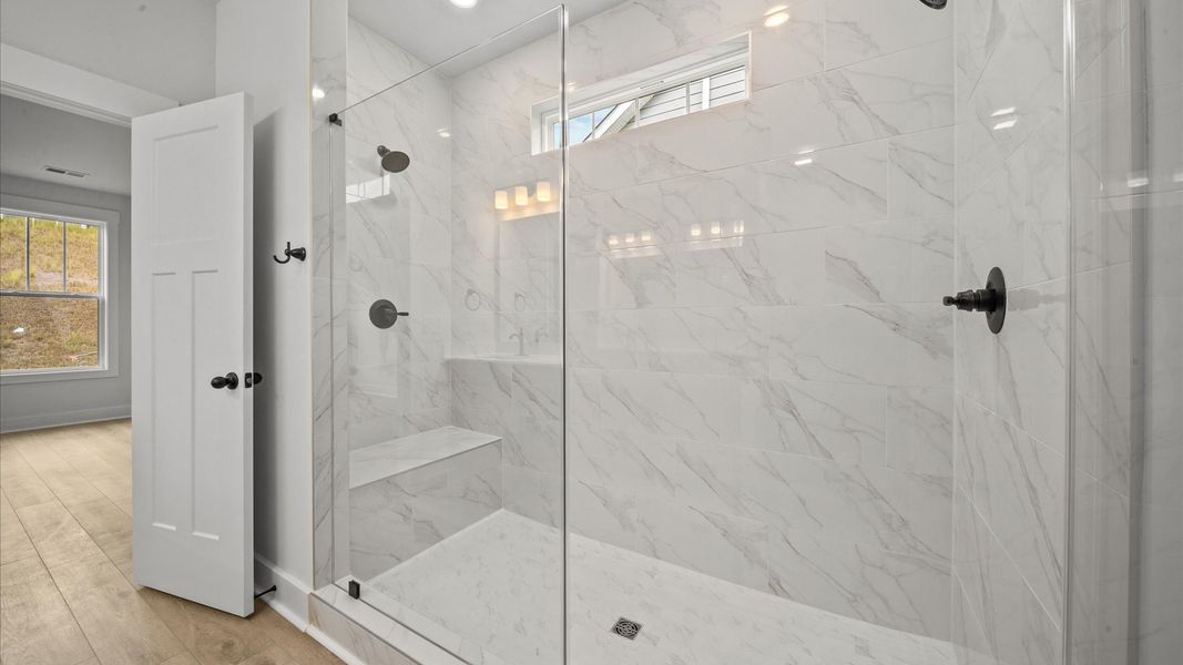 Superior en-suite primary bathroom with stylish tiled walk-in Roman shower—crafted with high standards in mind