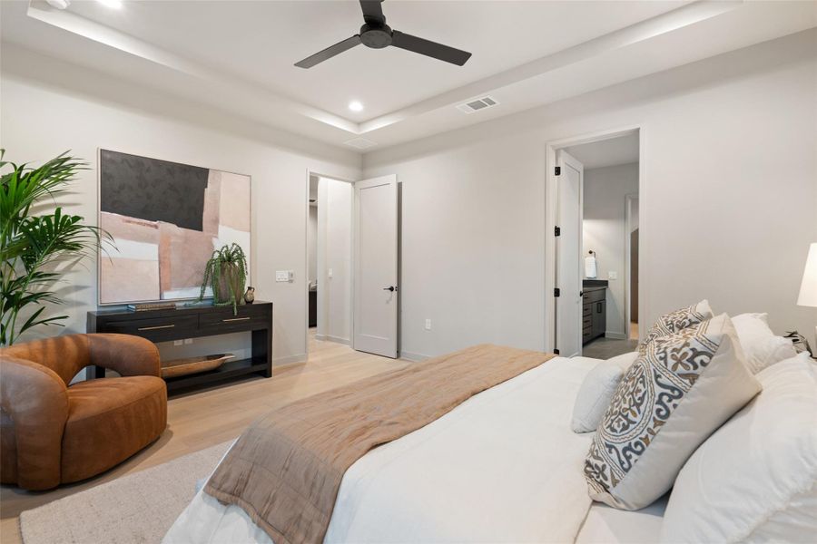 Recessed lighting illuminates this primary bedroom with sleek flooring.