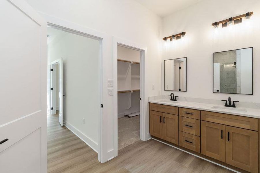 Bathroom featuring double vanity, light wood-style floors, and a walk in closet