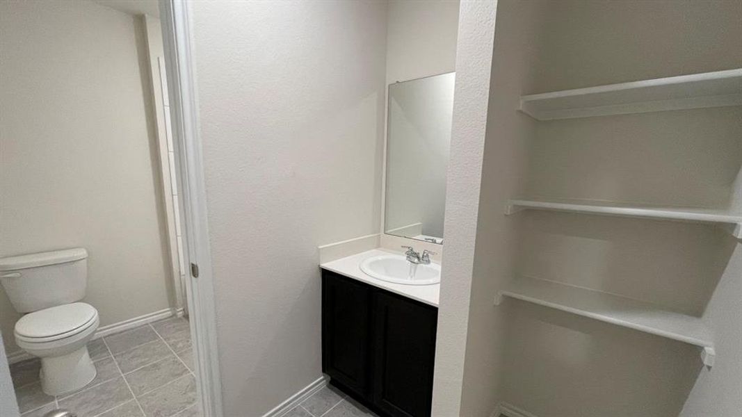 Built-in shelving unit providing storage, complemented by a vanity with a white countertop and dark wood-finish cabinetry