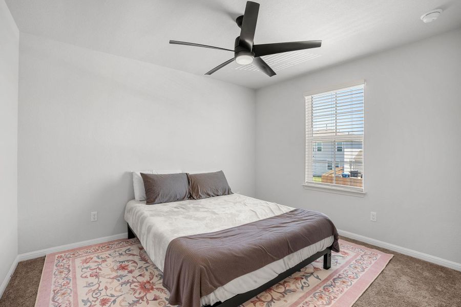 A quiet bedroom retreat with plush carpeting and a large window, ready for personalization.