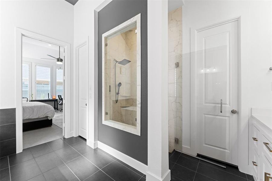 Ensuite bathroom with a stall shower, dark tile patterned flooring, vanity, and a ceiling fan Ensuite bathroom with a stall shower, dark tile patterned flooring, vanity, and a ceiling fan