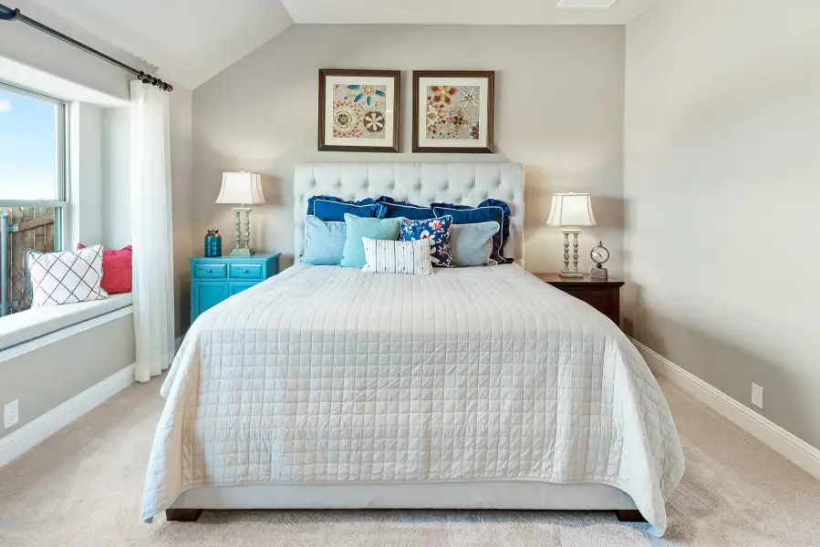 Bedroom with tufted upholstered headboard, white quilt, window seat, and vaulted ceiling Bedroom with tufted upholstered headboard, white quilt, window seat, and vaulted ceiling