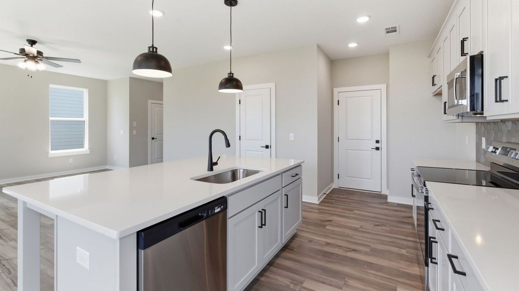 Kitchen with tile backsplash, pendant lighting, and quartz countertops