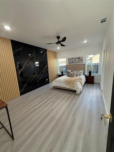 Primary Bedroom with multiple windows, Accent Wall, Luxury Plank Vinyl/wood-style Vinyl flooring, and ceiling fan