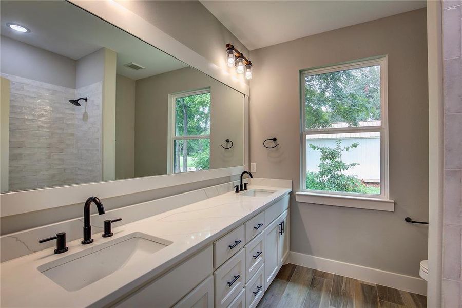 Bathroom with dual vanity, toilet, and wood-type flooring Bathroom with dual vanity, toilet, and wood-type flooring