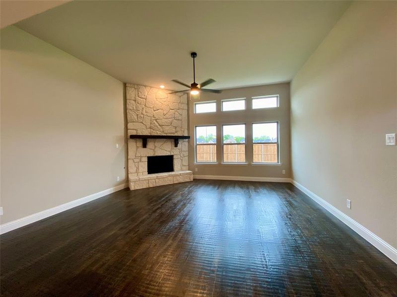 Family room offers a wall of windows, stone fireplace, Ebony hardwoods & a ceiling fan