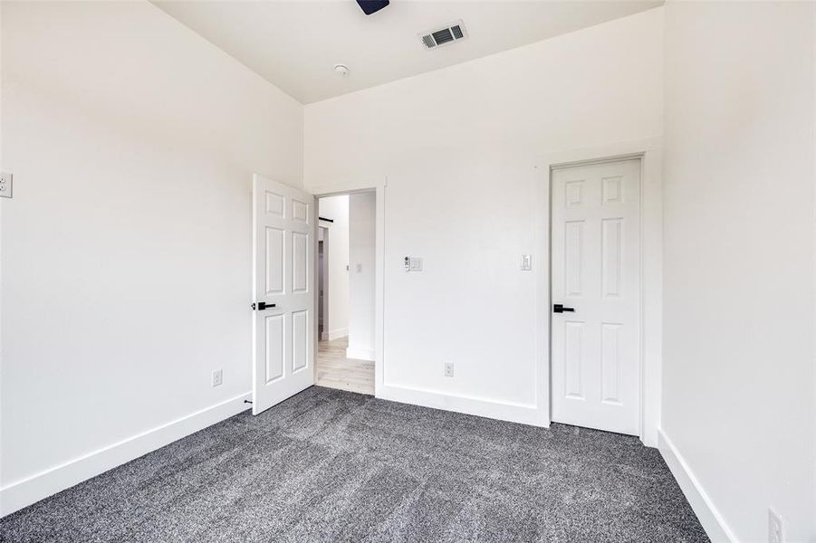 Unfurnished bedroom with dark colored carpet and baseboards Unfurnished bedroom with dark colored carpet and baseboards