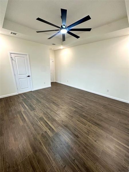 Unfurnished room with dark hardwood / wood-style flooring, a tray ceiling, and ceiling fan