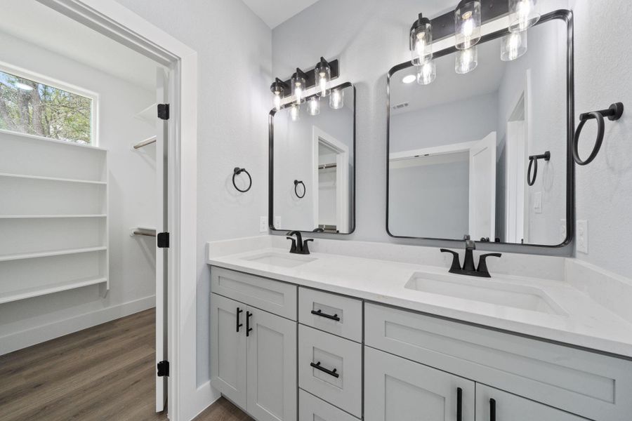 Dual vanities with white countertops, matte black fixtures, and framed mirrors