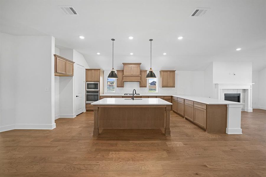 Kitchen featuring brown cabinetry, a peninsula, tasteful backsplash, dark wood-style floors, and recessed lighting Kitchen featuring brown cabinetry, a peninsula, tasteful backsplash, dark wood-style floors, and recessed lighting