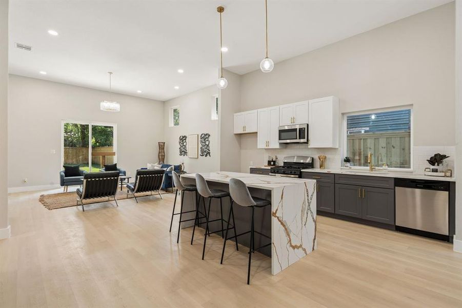 Open-concept living area featuring light wood-finish flooring and high ceilings Open-concept living area featuring light wood-finish flooring and high ceilings