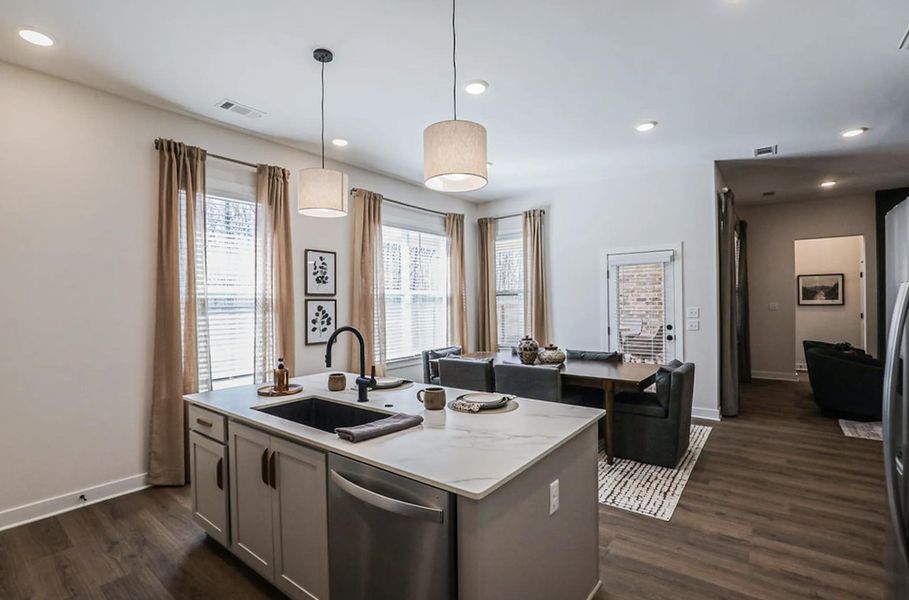 Kitchen island featuring a black sink and faucet, integrated dishwasher, and pendant lighting