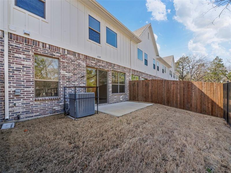 Rear view of property featuring brick siding, fence, and central air condition unit