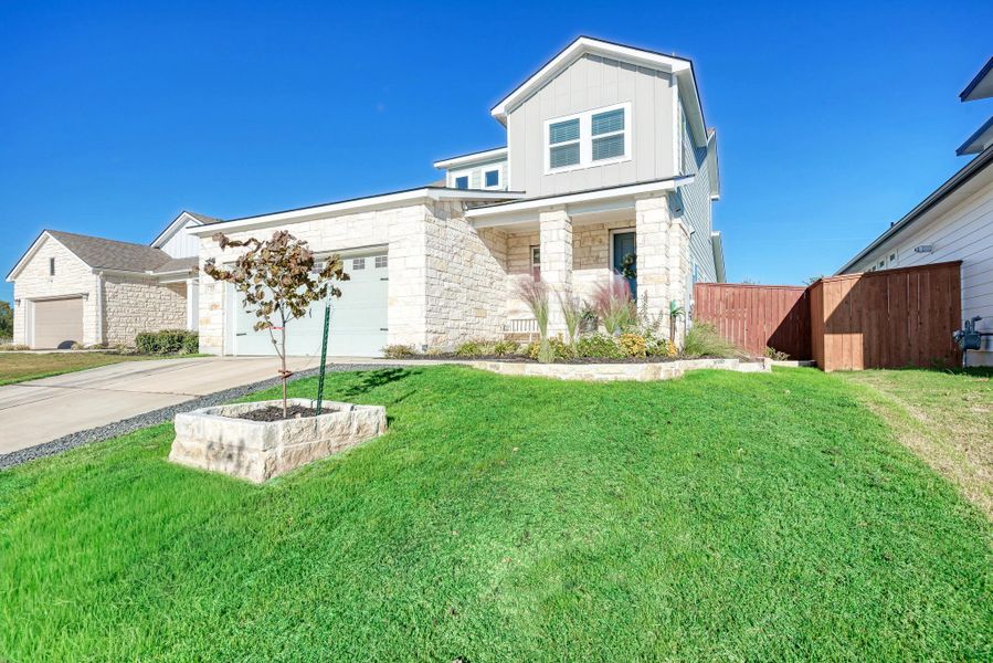 View of front of home featuring stone siding, concrete driveway, board and batten siding, a garage, and a porch