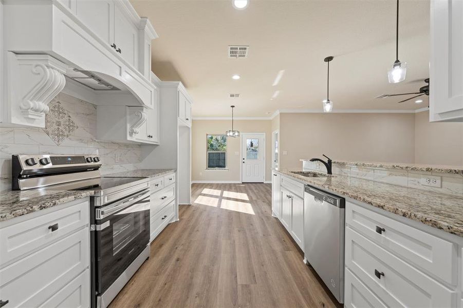 Kitchen featuring stainless steel appliances, crown molding, tasteful backsplash, white cabinetry, and light wood finished floors