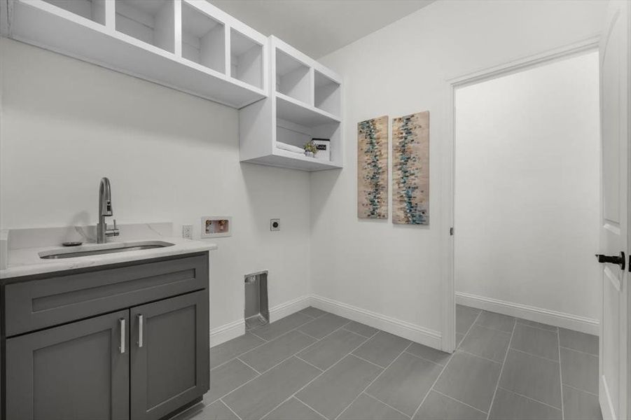 Washroom featuring sink, electric dryer hookup, hookup for a washing machine, cabinets, and dark tile patterned flooring