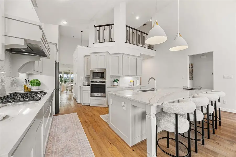 Kitchen with light stone countertops, a breakfast bar area, light wood-type flooring, a sink, and appliances with stainless steel finishes