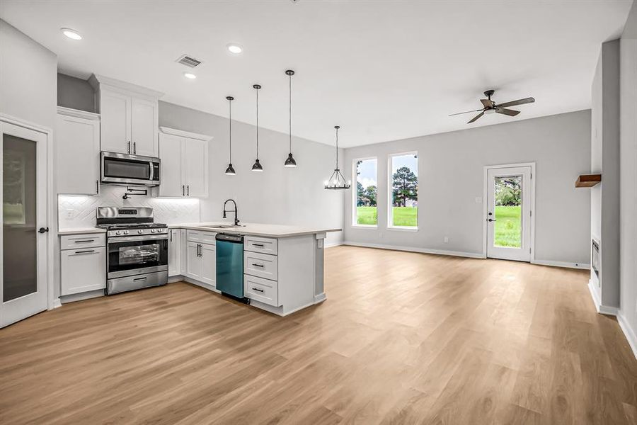 Kitchen is open to the living and dining space for an open concept floor plan. The space is filled with natural light from the large windows.