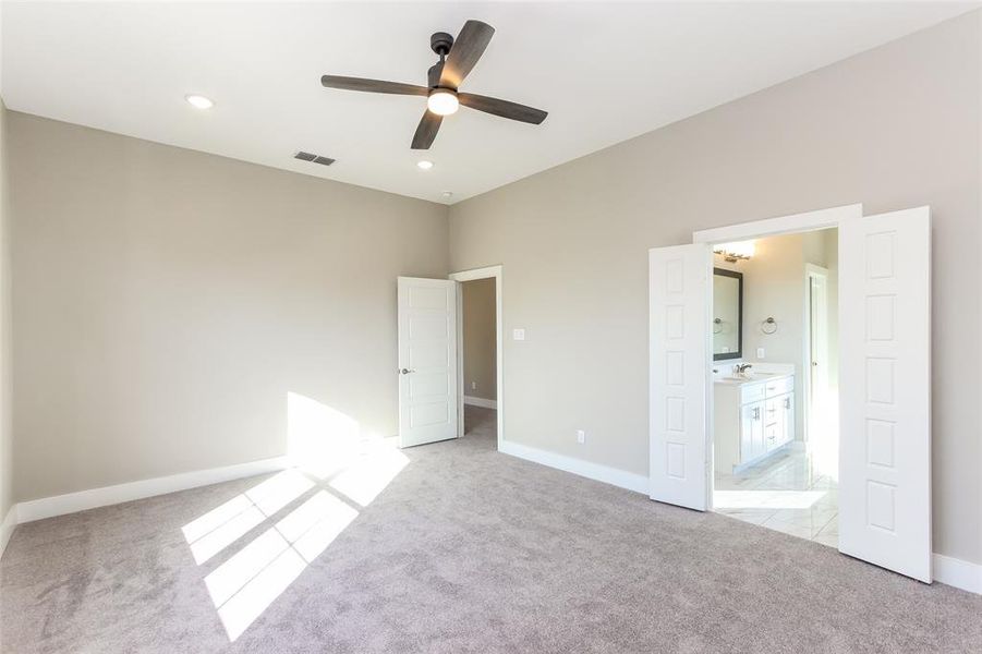 Unfurnished bedroom with sink, ceiling fan, connected bathroom, and light colored carpet