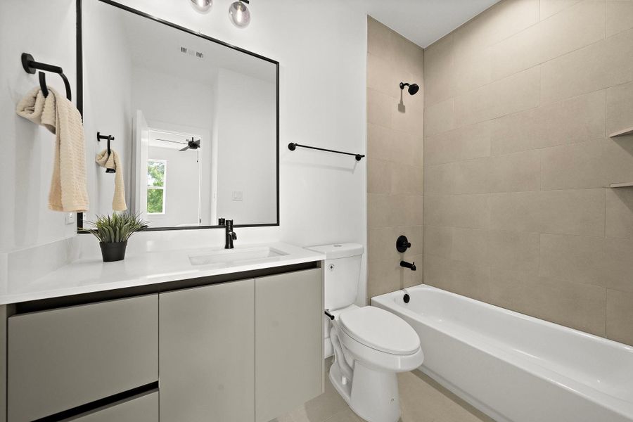 This secondary ensuite bathroom on the third floor features modern fixtures, a sleek vanity, and a shower-tub combo. This secondary ensuite bathroom on the third floor features modern fixtures, a sleek vanity, and a shower-tub combo.
